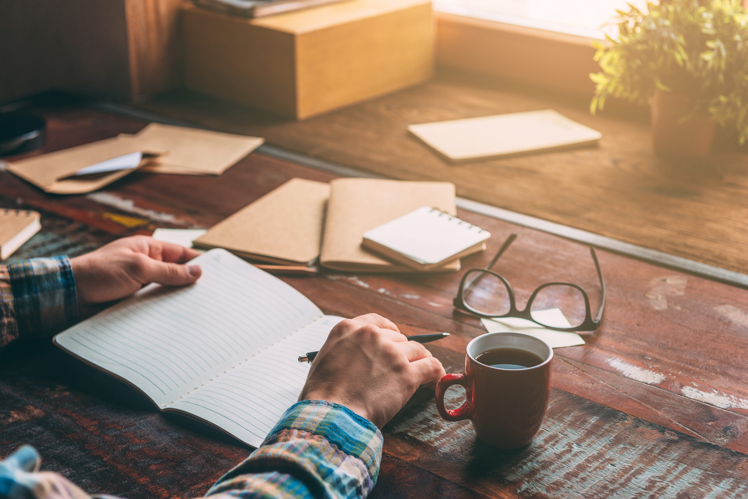 making some notes. close up image of man writing in notebook while sitting at the rustic wooden table